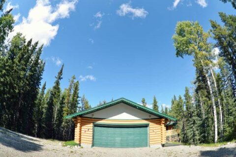 A log cabin with a garage in the woods