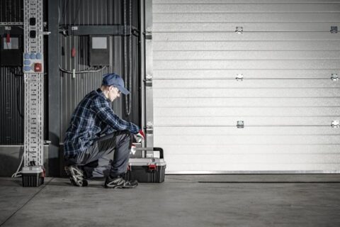 A person squatting next to a garage door