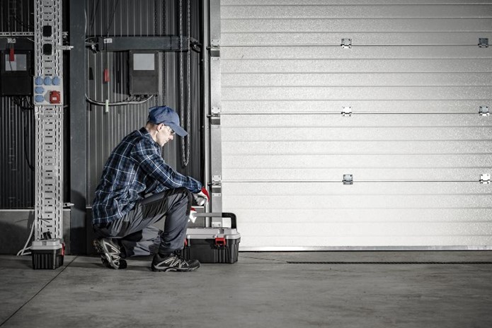 A person squatting next to a garage door